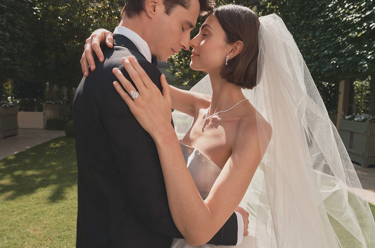 Female and male model embrace, female model wears Graff Promise pear shape engagement ring and Graff bridal jewellery