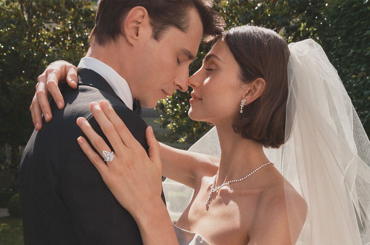 Female and male model embrace, female model wears Graff Promise pear shape engagement ring and Graff bridal jewellery